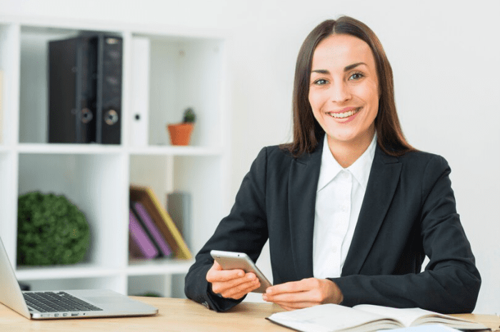 Mulher sorridente com celular na mãos.